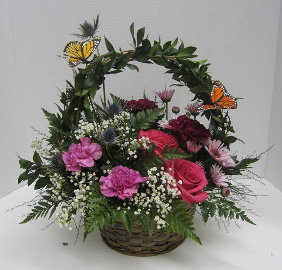 a mixture of carnation, roses and mums with a couple of colorful butterflies.